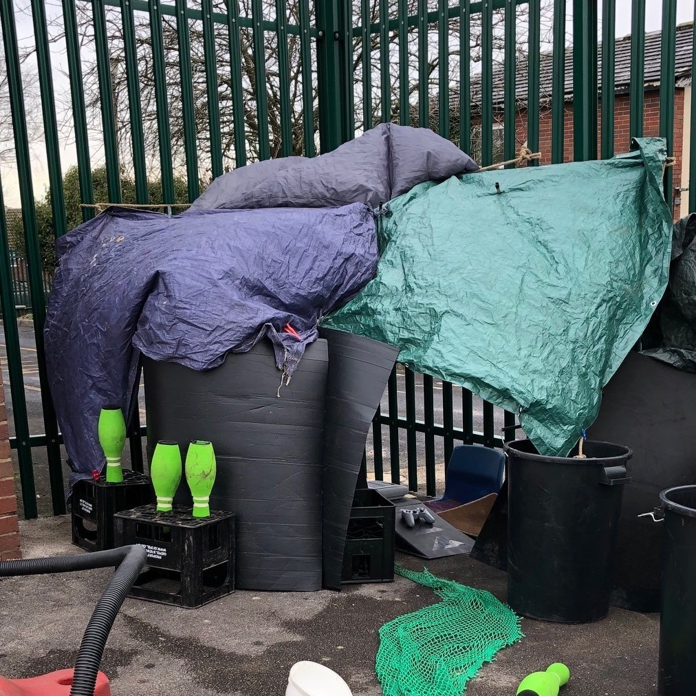 A children's den made from tarpaulin, card and plastic drinks crates.